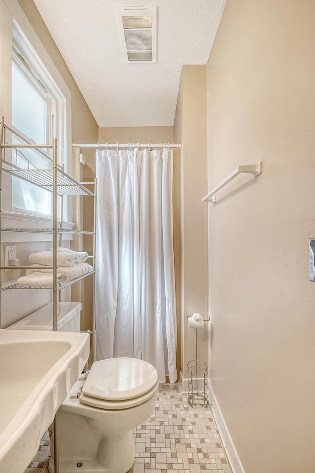 bathroom with a textured ceiling, sink, and toilet