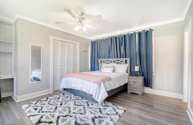 bedroom featuring a closet, a textured ceiling, hardwood / wood-style flooring, ornamental molding, and ceiling fan