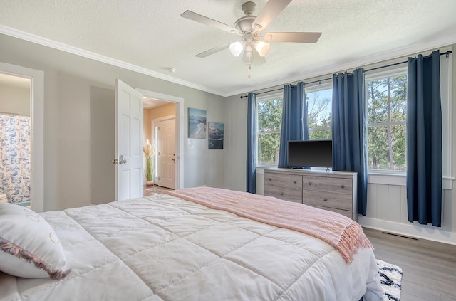 bedroom featuring ornamental molding, ceiling fan, multiple windows, and hardwood / wood-style floors