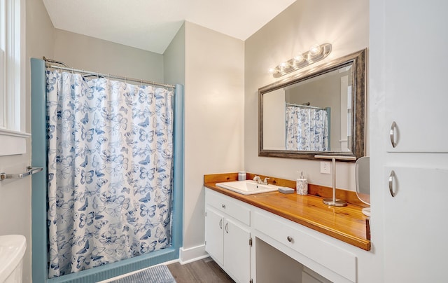 bathroom featuring a shower with shower curtain, hardwood / wood-style floors, vanity, and toilet