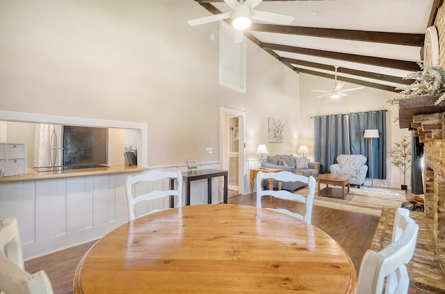 dining space featuring beamed ceiling, a fireplace, high vaulted ceiling, hardwood / wood-style floors, and ceiling fan