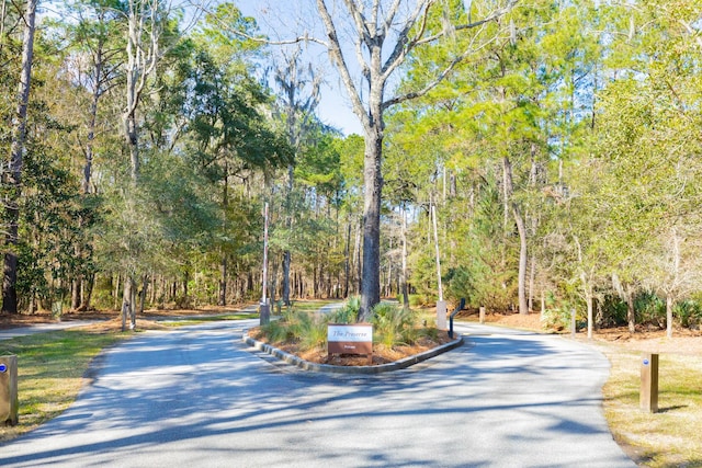 view of property's community with aphalt driveway and a wooded view