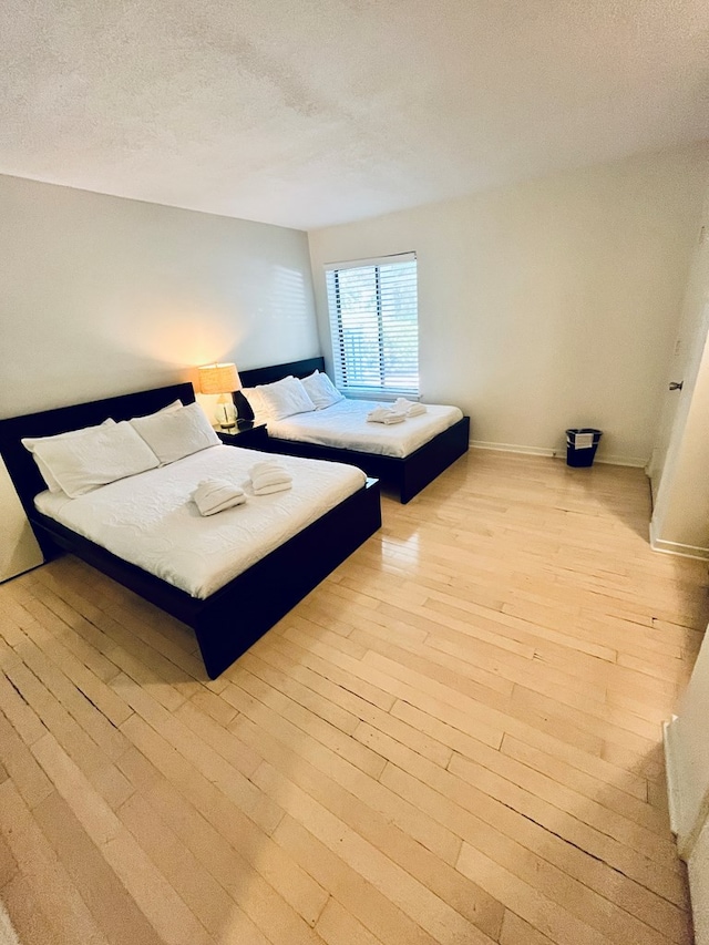 bedroom featuring a textured ceiling and light hardwood / wood-style flooring