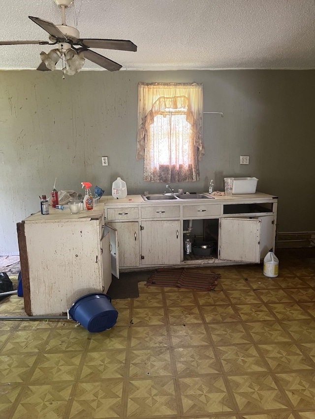 kitchen featuring parquet flooring, a textured ceiling, ceiling fan, and sink