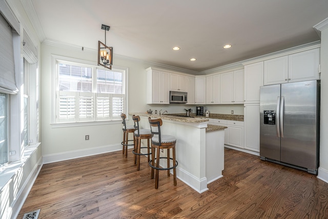 kitchen with appliances with stainless steel finishes, ornamental molding, dark wood finished floors, and white cabinets