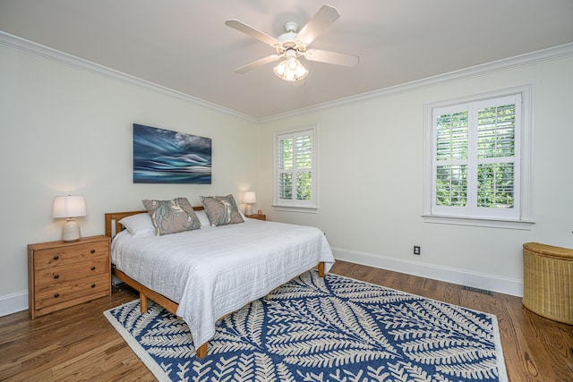 bedroom featuring a ceiling fan, visible vents, wood finished floors, baseboards, and ornamental molding
