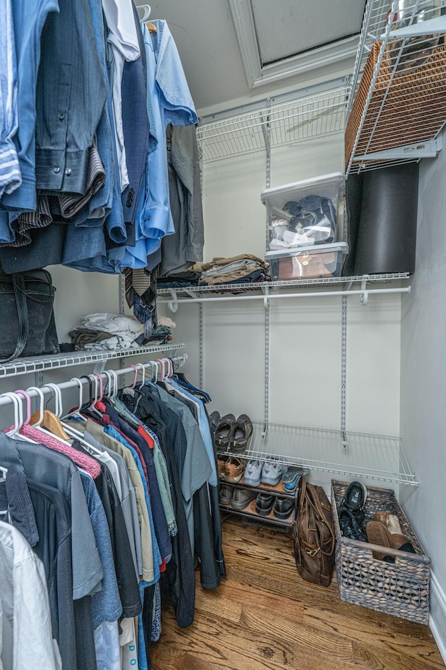 walk in closet with attic access and wood finished floors