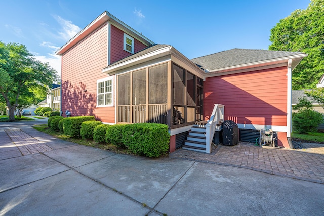 back of house with a shingled roof and a sunroom