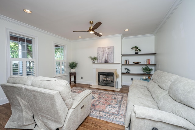 living room featuring crown molding, ceiling fan, a fireplace with flush hearth, and wood finished floors