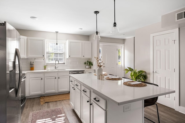 kitchen with decorative light fixtures, a center island, sink, and appliances with stainless steel finishes