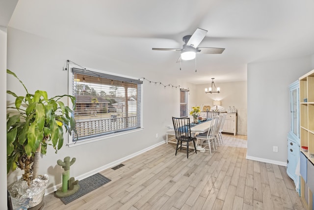 dining space featuring ceiling fan with notable chandelier and light hardwood / wood-style flooring