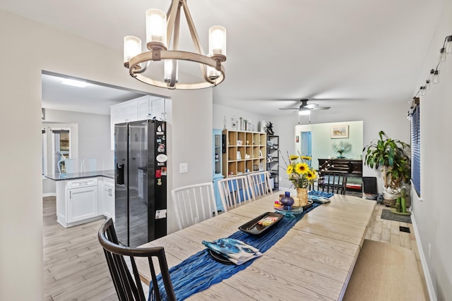 dining area featuring ceiling fan with notable chandelier and light hardwood / wood-style flooring