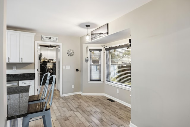 kitchen with white cabinetry, hanging light fixtures, built in desk, and light hardwood / wood-style floors