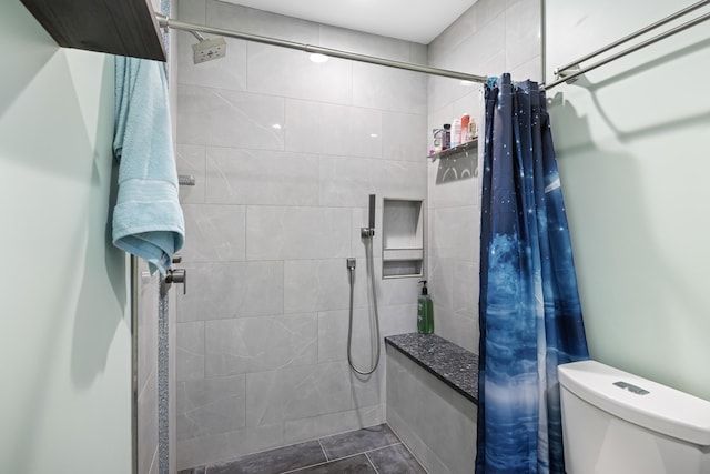 bathroom featuring tile patterned flooring, toilet, and walk in shower