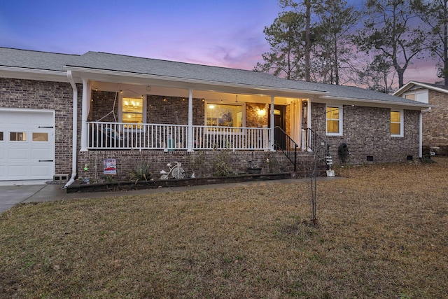 single story home featuring a porch, a garage, and a lawn