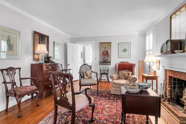 living room featuring baseboards, a brick fireplace, wood finished floors, and ornamental molding