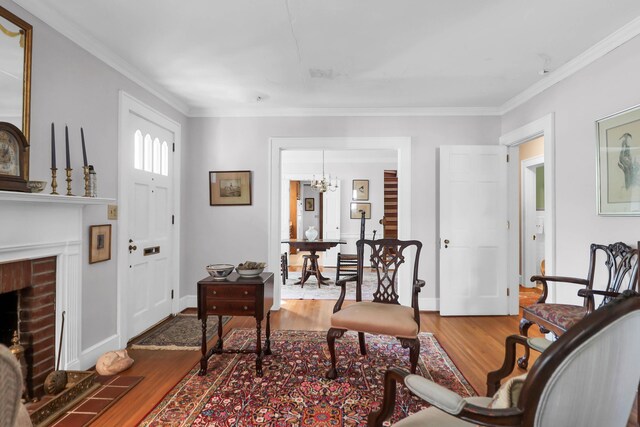 living area featuring wood finished floors, a brick fireplace, and ornamental molding