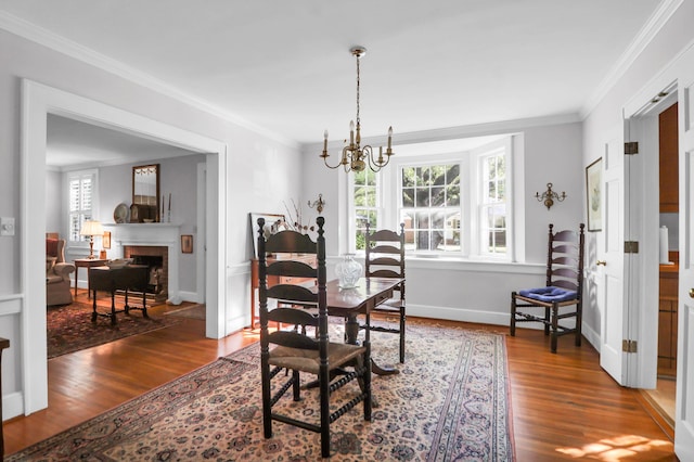 dining area featuring dark wood-style floors, baseboards, a notable chandelier, a fireplace, and ornamental molding