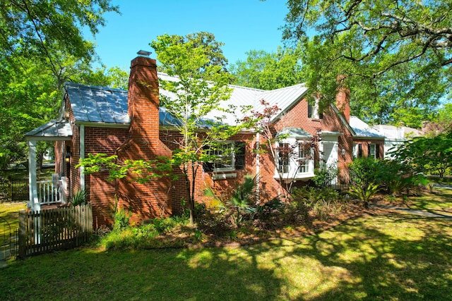 rear view of property with brick siding, a lawn, and a chimney