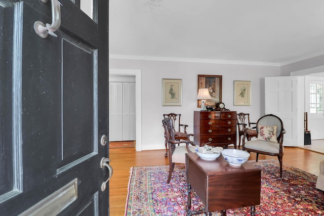 living room with light wood-type flooring, baseboards, and ornamental molding