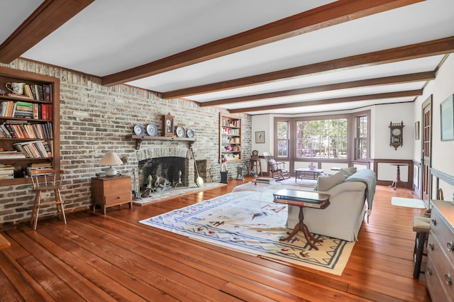 living area featuring brick wall, hardwood / wood-style flooring, beam ceiling, and a fireplace