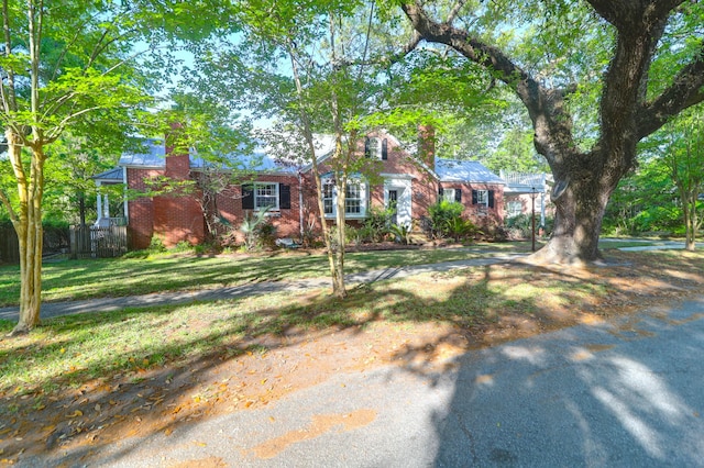 view of front of home featuring fence, a front lawn, a chimney, and brick siding