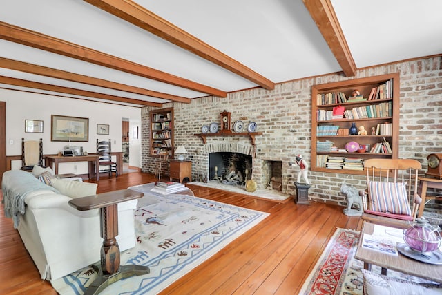living room with beamed ceiling, wood-type flooring, a brick fireplace, and brick wall