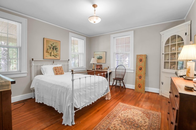 bedroom featuring wood finished floors, baseboards, and multiple windows