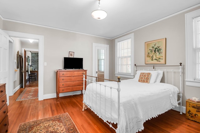 bedroom with baseboards, wood finished floors, and crown molding