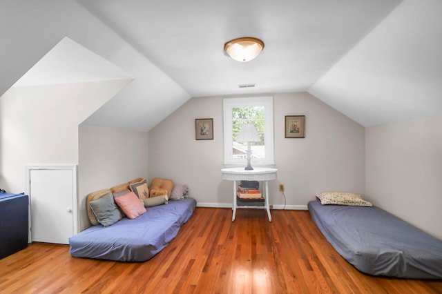 bedroom with wood finished floors, visible vents, and lofted ceiling
