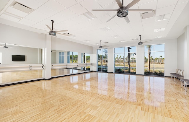 workout area with a drop ceiling, a ceiling fan, a healthy amount of sunlight, and visible vents