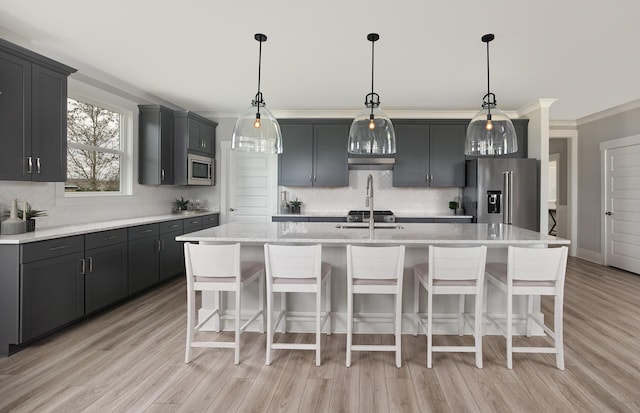 kitchen with decorative backsplash, a center island with sink, a kitchen breakfast bar, and appliances with stainless steel finishes