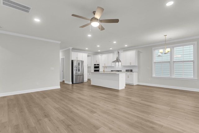 unfurnished living room featuring visible vents, baseboards, ornamental molding, light wood-style floors, and ceiling fan with notable chandelier