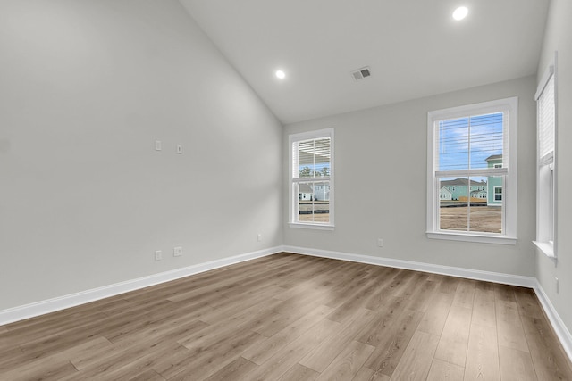 empty room with visible vents, wood finished floors, a wealth of natural light, and baseboards