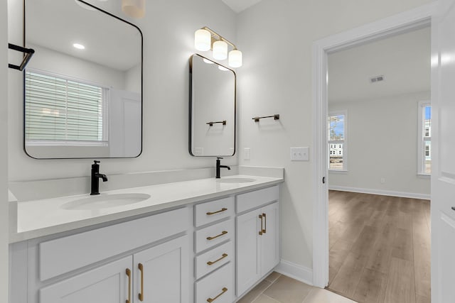 bathroom featuring double vanity, baseboards, visible vents, and a sink