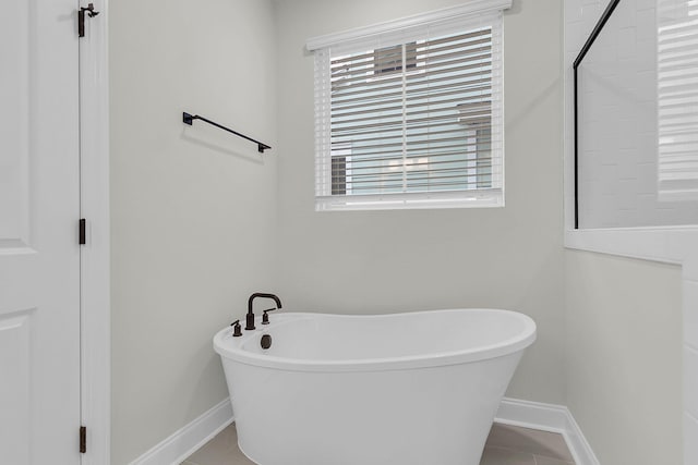 bathroom featuring a freestanding bath, tile patterned floors, and baseboards