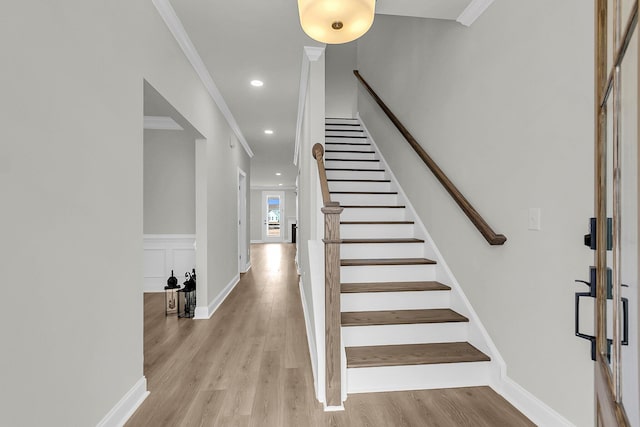 staircase with a wainscoted wall, ornamental molding, wood finished floors, and recessed lighting