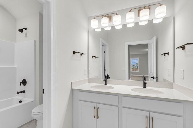 bathroom featuring double vanity, washtub / shower combination, toilet, and a sink