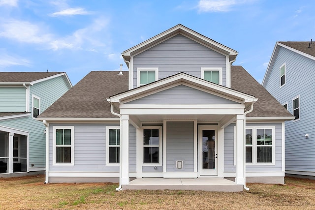 back of property featuring a patio area, a lawn, and roof with shingles