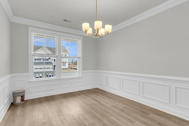 unfurnished dining area featuring crown molding, light wood-type flooring, visible vents, and a notable chandelier