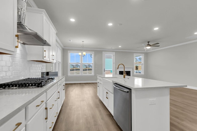 kitchen with wall chimney range hood, ornamental molding, stainless steel appliances, and decorative backsplash