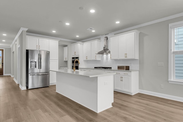 kitchen with stainless steel appliances, ornamental molding, wall chimney range hood, decorative backsplash, and an island with sink