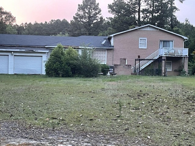 495 Majority Rd, Orangeburg, SC 29118 - back of house at dusk featuring a yard, brick siding, a garage, and stairs