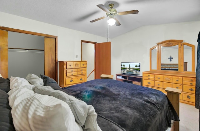 bedroom with vaulted ceiling, ceiling fan, a textured ceiling, light colored carpet, and a closet