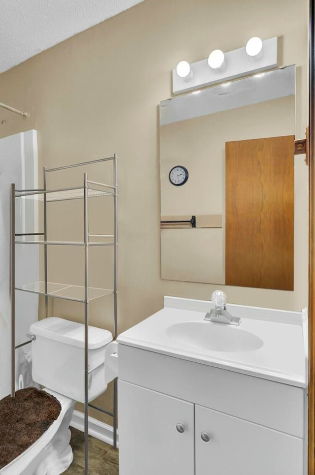 bathroom with vanity, toilet, a textured ceiling, and walk in shower