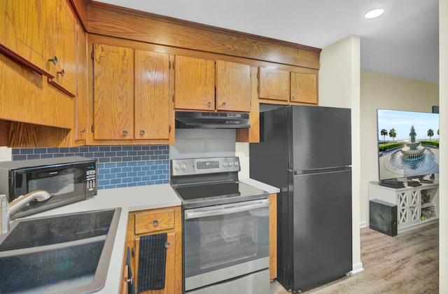 kitchen with light wood-type flooring, sink, backsplash, and black appliances