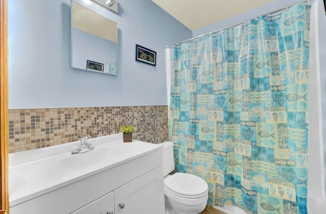 bathroom with a textured ceiling, vanity, tile walls, toilet, and curtained shower