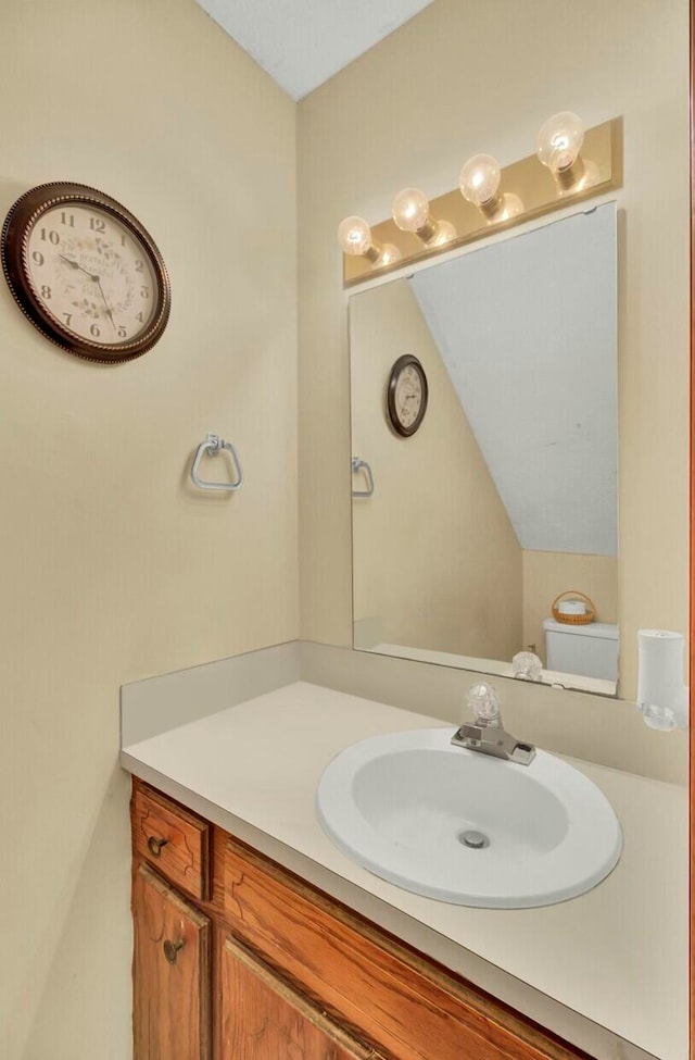 bathroom with vanity, toilet, and vaulted ceiling