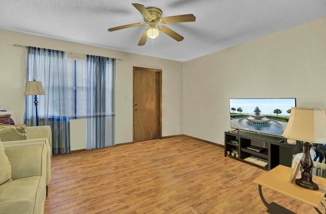 living room featuring ceiling fan, light hardwood / wood-style floors, and a textured ceiling