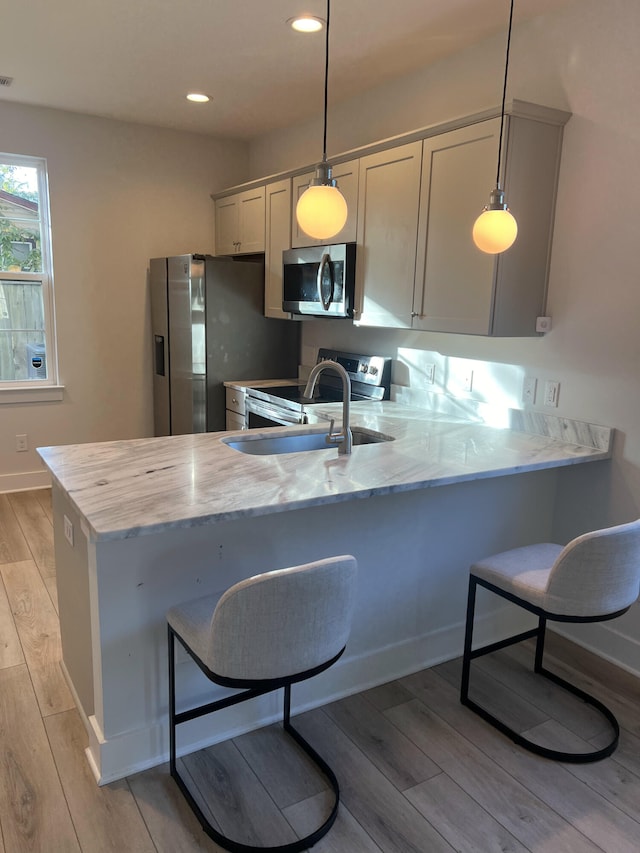 kitchen featuring pendant lighting, stainless steel appliances, a kitchen breakfast bar, and kitchen peninsula